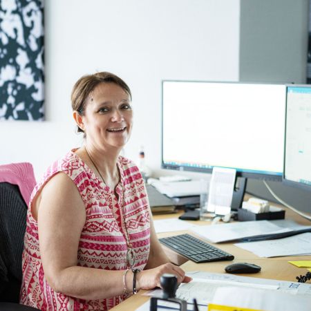 Lächelnde Frau im Büro der Rechtsanwaltskanzlei PLUP am Schreibtisch 